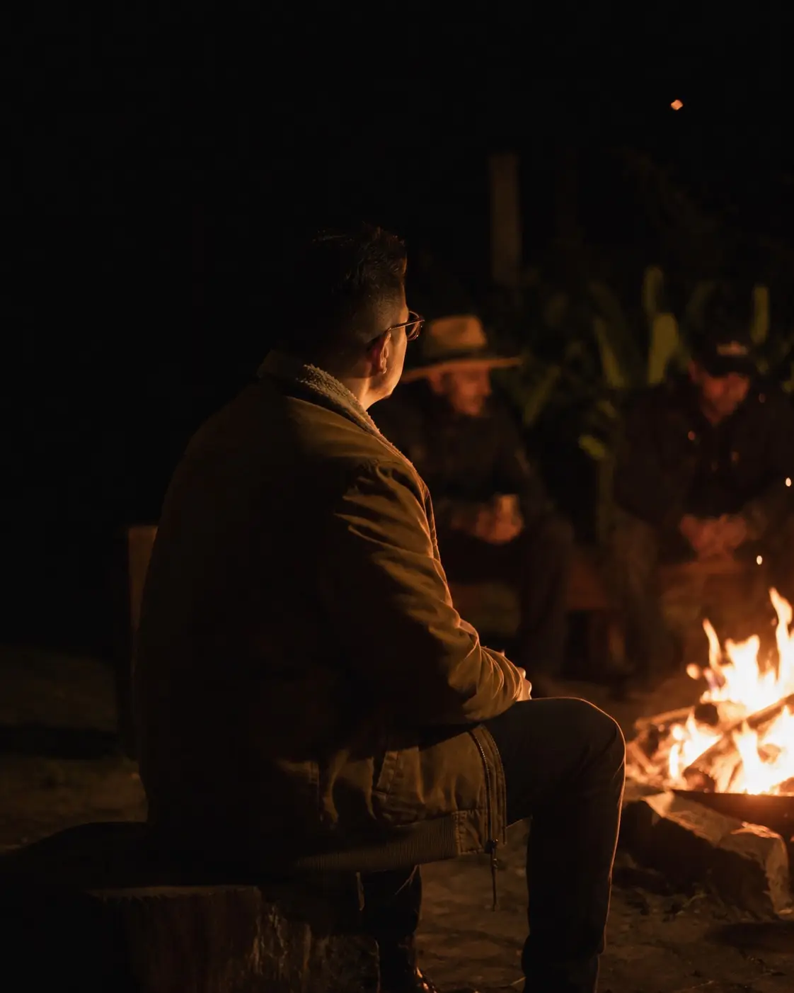 Hombres sentados alrededor de un fuego, de noche, en un círculo de La Forja